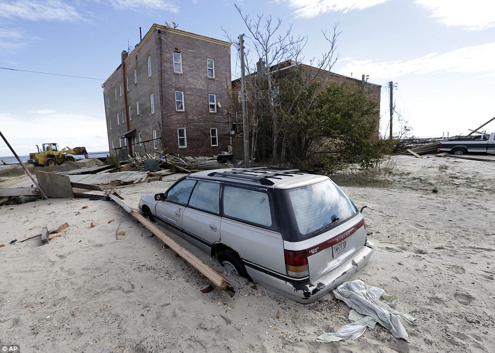 Stuck: A car is pictured on Wednesday, partially buried by sand that was washed ashore by Superstorm Sandy in Atlantic City, New Jersey